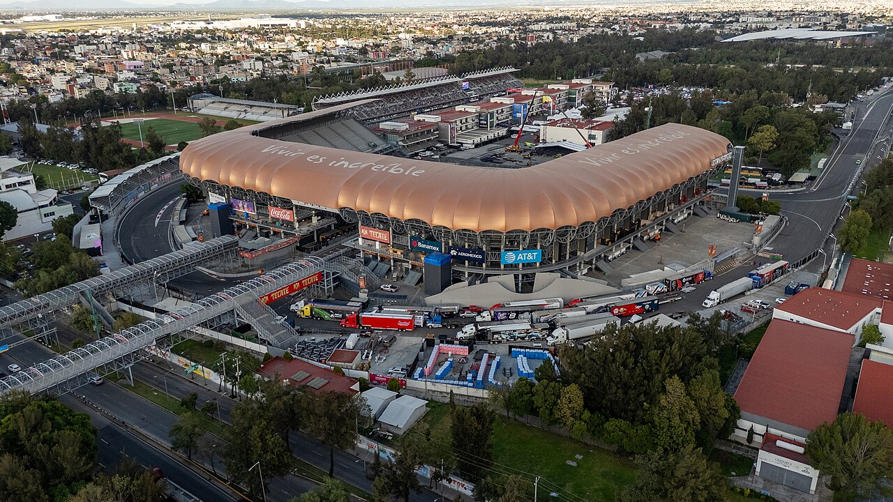 Aerial view of a large stadium with a curved roof beside the race track in Mexico City