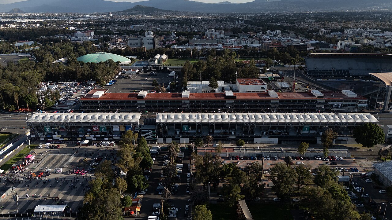 Aerial view of the main grandstand and pit building at the Mexico City circuit, with the city behind